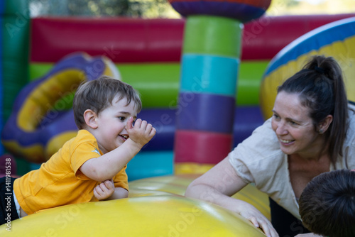 Happy child playing on inflatable bouncy castle with mother