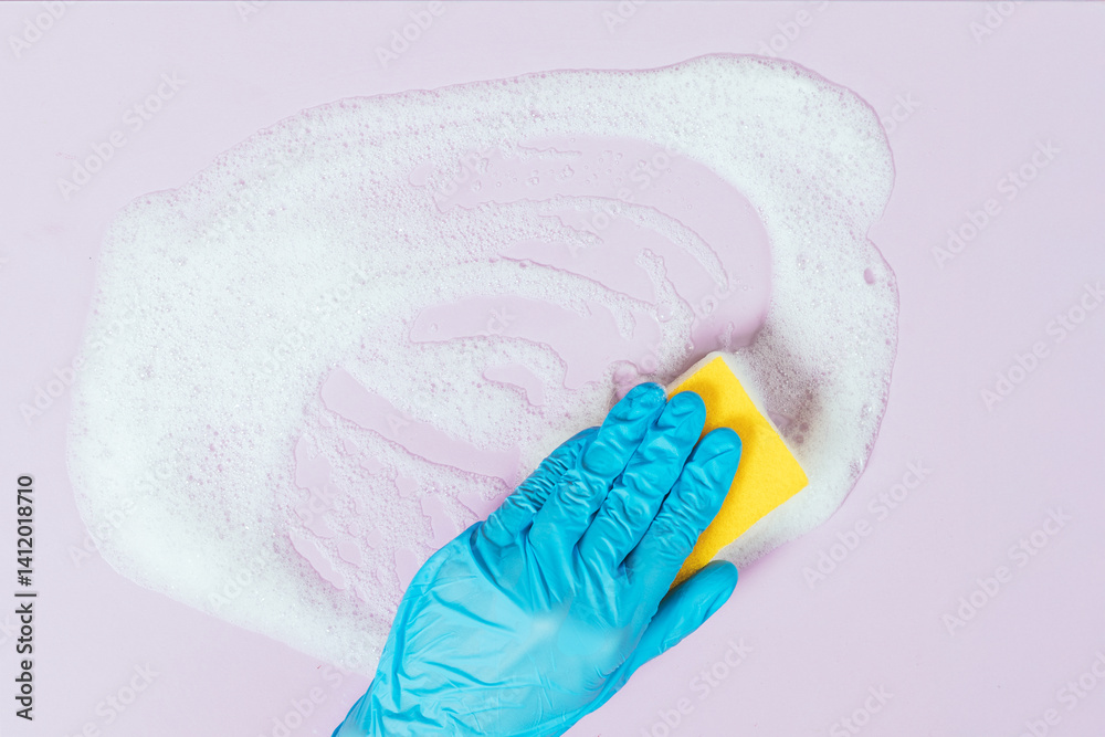 A person is cleaning a surface with a sponge and a blue glove