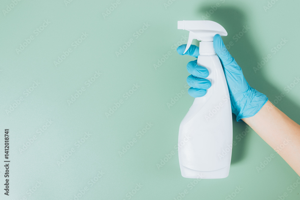 A person is holding a spray bottle with a blue glove on their hand