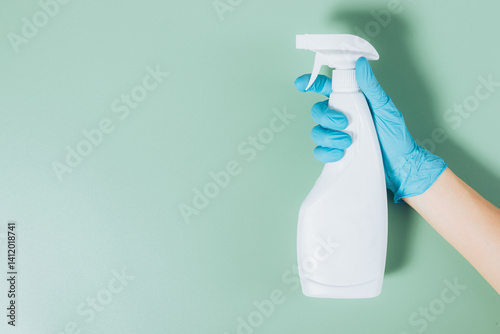 Obraz na płótnie A person is holding a spray bottle with a blue glove on their hand w salonie