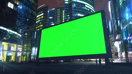 Green screen billboard mockup at night with business people walking