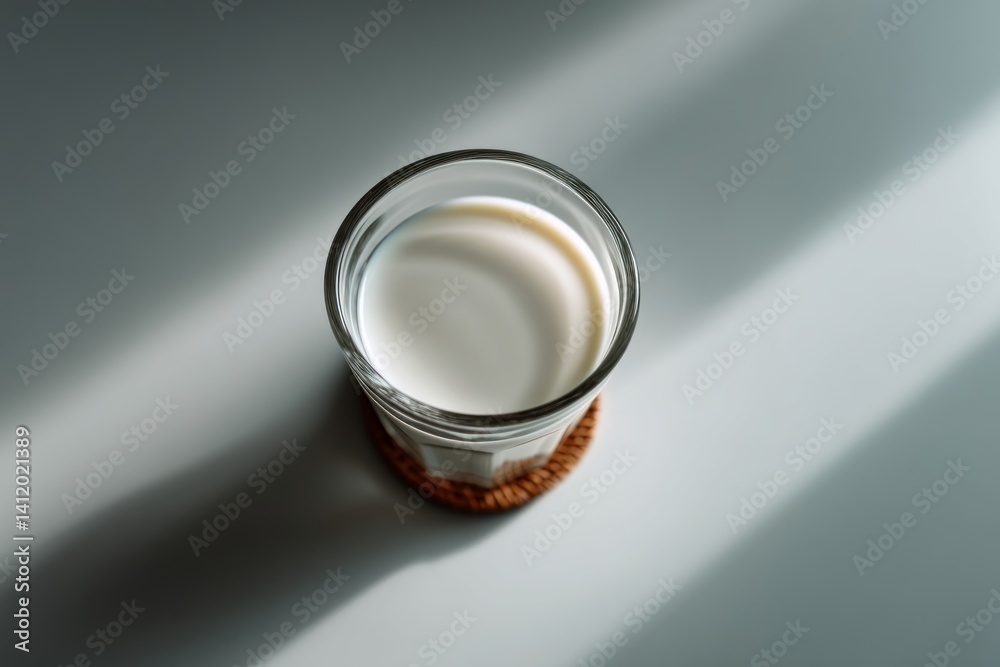 Fresh Milk in a Clear Glass on a Simple Gray Background with Natural Light Shadows