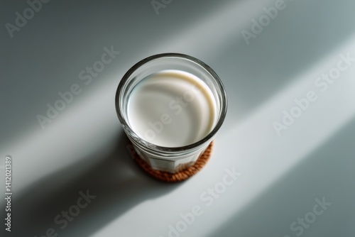 Fresh Milk in a Clear Glass on a Simple Gray Background with Natural Light Shadows