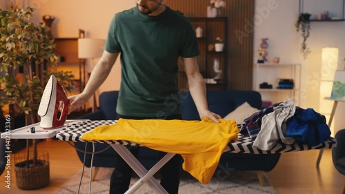 Young male carefully ironing clothes, meticulous man doing household chores