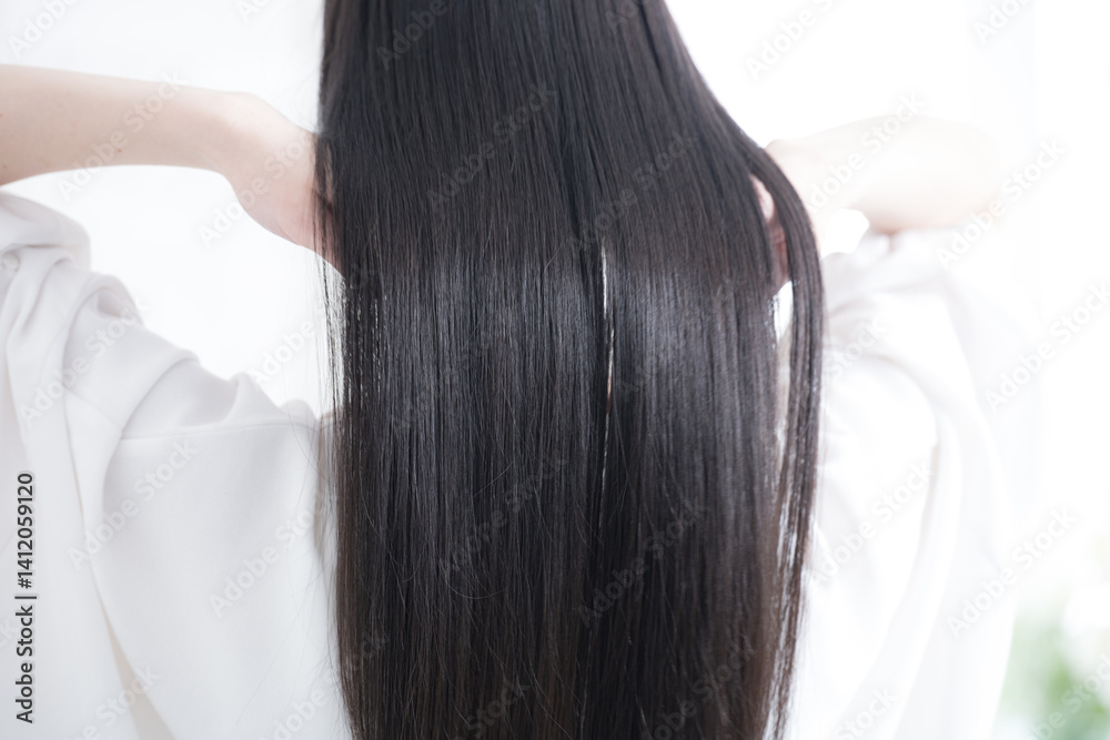 Fototapeta premium 艶のあるロングヘアの黒髪の女性の後ろ姿の顔無し キューティクルな美しいストレートヘアの髪の毛 ヘアケアなどのイメージ