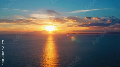 Peaceful sunset over the ocean, with a reflection on the water and clouds above. A beautiful beach scene.