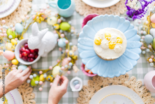 Easter Table setting with cakes on platters with hands setting up