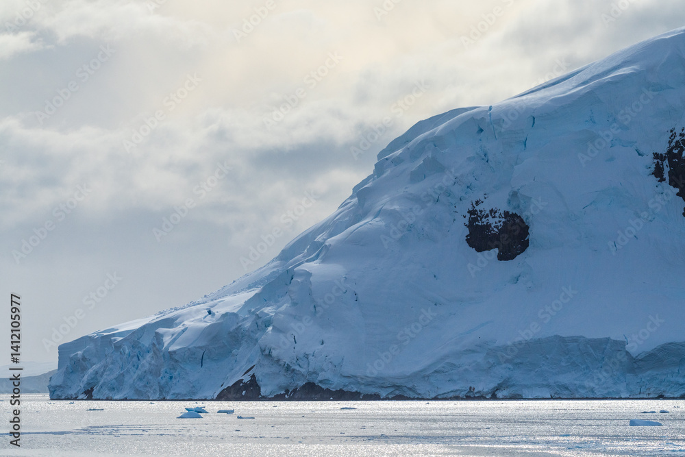 A tranquil Antarctic landscape, near Graham passage along Charlotte Bay, highlighting stark reflections, rugged mountains, and impressive icebergs.