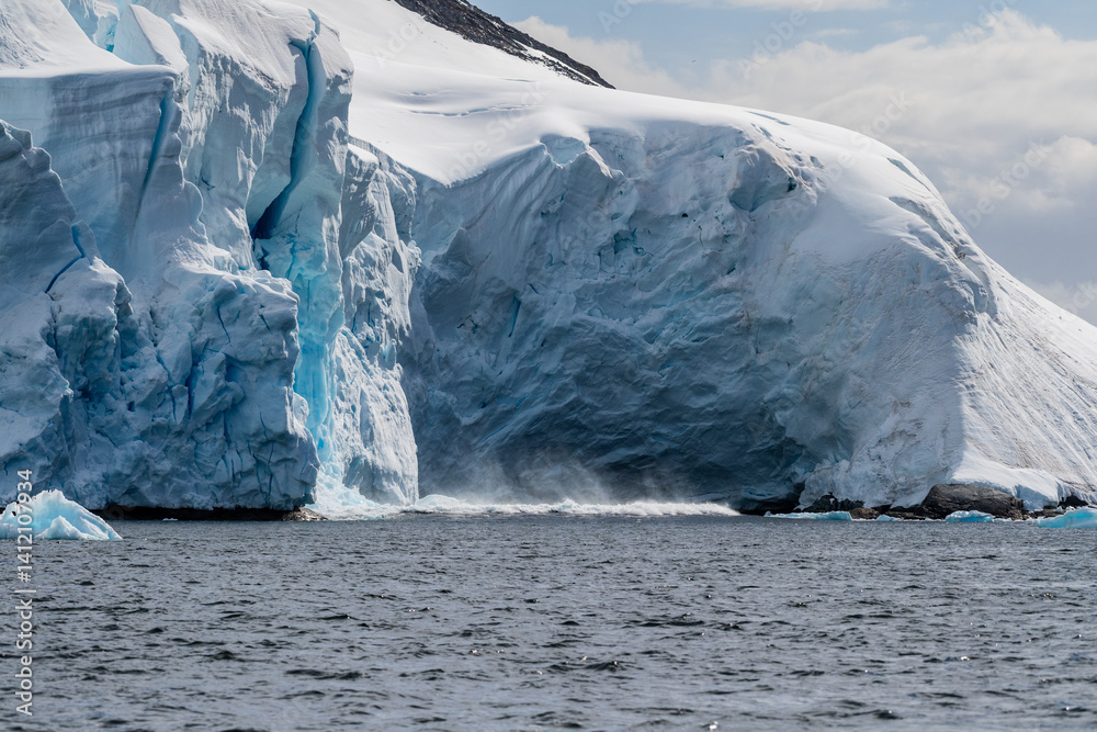 Telephoto of a giant chunk of ice calving off an ice sheet. Graham Passage, near Charlotte Bay, on the Antarctic Peninsula