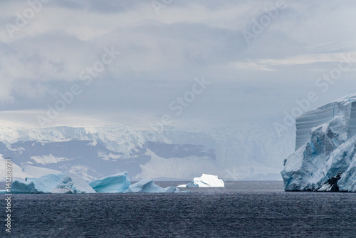 Obraz na płótnie A tranquil Antarctic landscape, near Graham passage along Charlotte Bay, highlighting stark reflections, rugged mountains, and impressive icebergs. w salonie