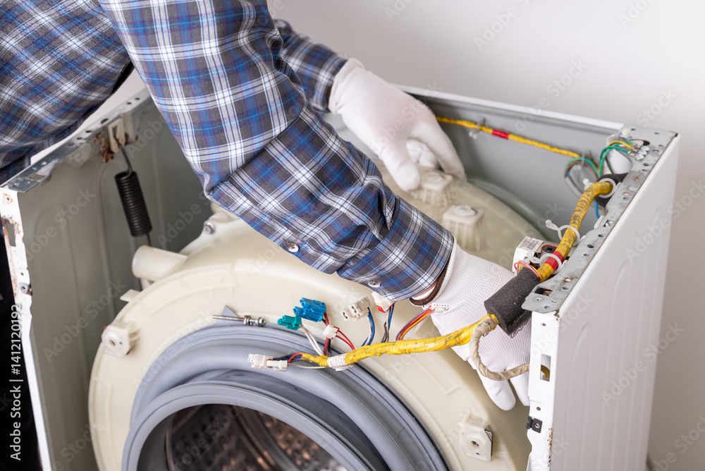 Repair service for washing machine with technician working on device internals. A technician repairs a washing machine, examining internal parts and wiring in a service environment Repair service for washing machine with technician working on device internals. A technician repairs a washing machine, examining internal parts and wiring in a service environment
