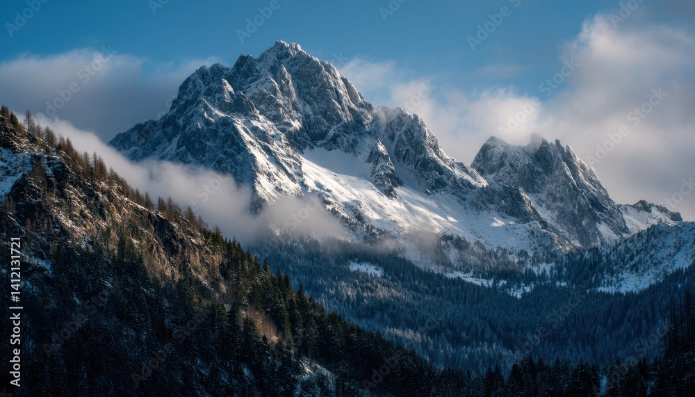 Fototapeta premium Majestic snow-capped peaks dominate the landscape of the Alps, surrounded by dense forests and a bright blue sky