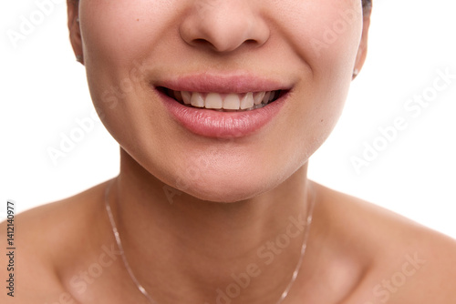 Cropped image of tender female smile, woman with smooth, spotless skin, white teeth and plump pink lips against white background. Concept of natural beauty, dental care, medical treatment, wellness