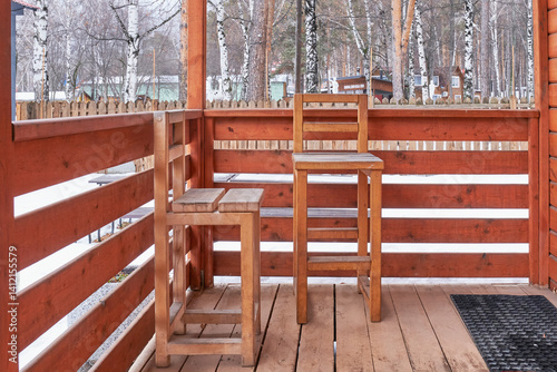 Foto Rustic wooden porch with two high wooden chairs, enclosed by wooden railing