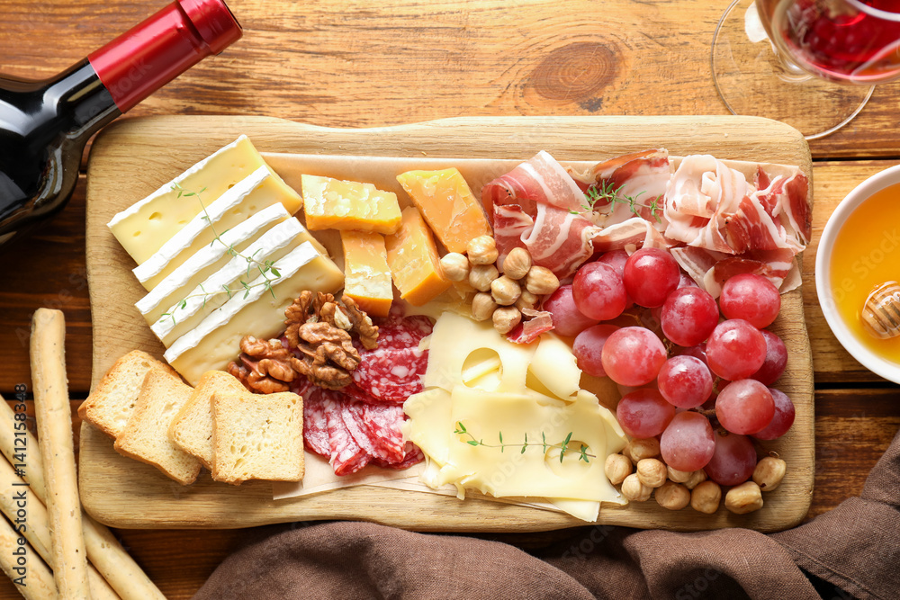 Different types of cut cheese and other snacks served with wine on wooden table, flat lay