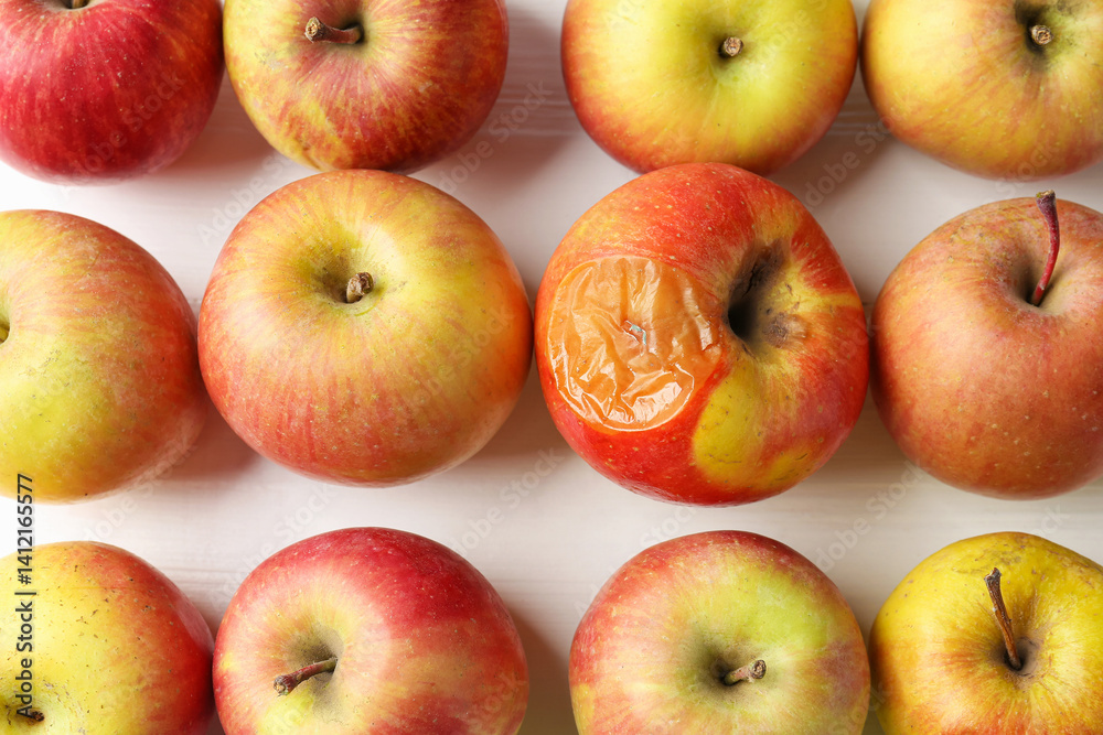 Rotten apple among fresh ones on white wooden table, flat lay Rotten apple among fresh ones on white wooden table, flat lay