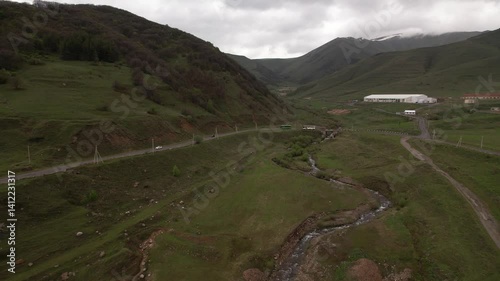 Aerial view of a lush green landscape with winding roads and cars navigating alongside mountains photo