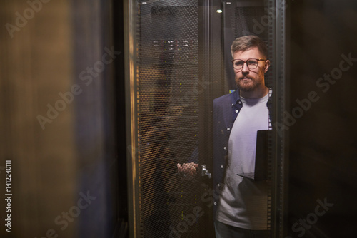 Portrait of man in a modern server room inspecting servers with focus on technology and equipment working environment without any unnecessary details
