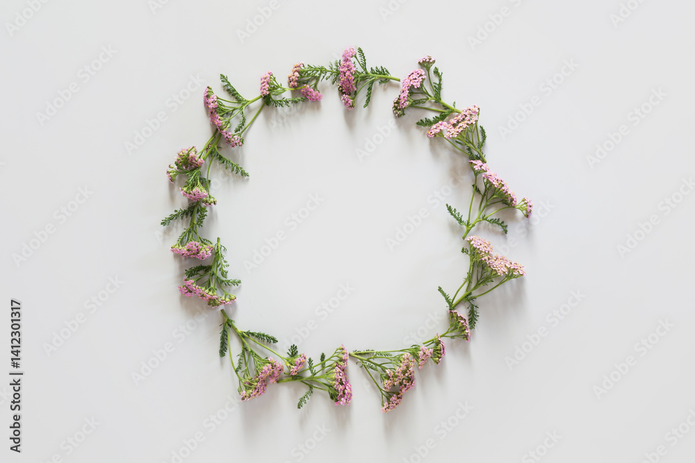 Wreath of wild purple and pink flowers on grey background. Flat lay. View from above. Space for text.