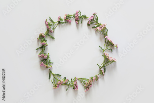 Wreath of wild purple and pink flowers on grey background. Flat lay. View from above. Space for text.