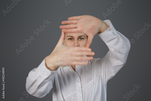 The woman shows her hands only in close-up of her eyes on a gray background. The girl covered her face, leaving only her eyes visible, the woman on the background, space for copy, text and advertising