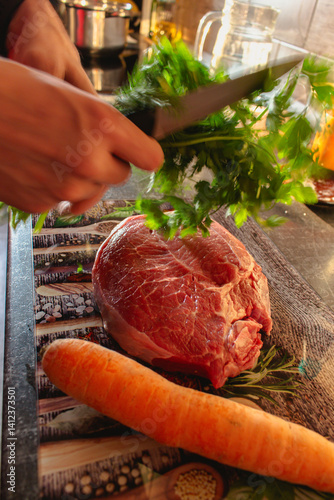 Obraz na płótnie Man with fork in motion with raw beaf steak, carrot and parsley on cutting board. Raw meat, herbs and vegetable on table. Meat preparation in motion. Steak preparation process. Food styling. w salonie