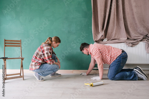 couple renovating new house or apartment, attaching new baseboard photo