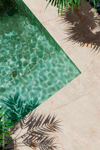.Top view of luxury swimming pool with palm shadow and marble floor. Summer background for tropical holiday vacation. Modern hotel villa, poolside water from above. Product placement showroom design.