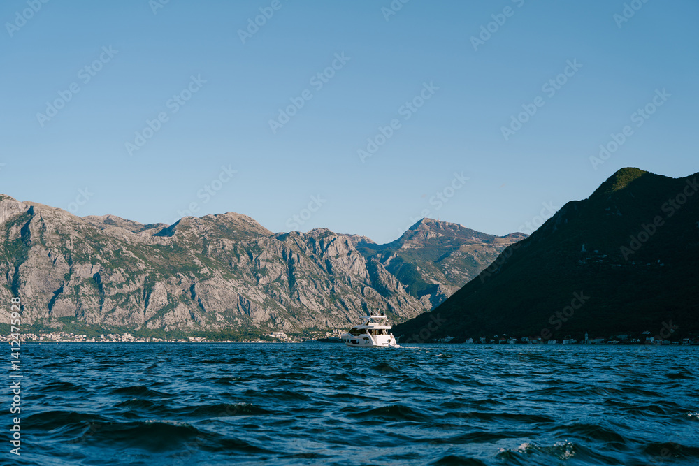 Boat floats on the blue sea against the backdrop of a high mountain range Boat floats on the blue sea against the backdrop of a high mountain range
