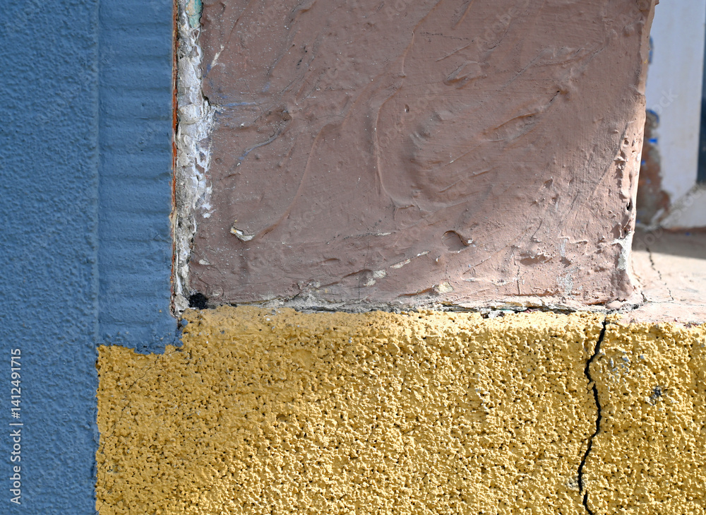 Colorful wall corner showcasing textures and paint variations in a sunny outdoor setting