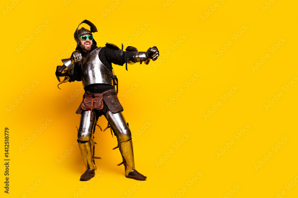 Young man in medieval armor displaying a humorous pose on a vibrant yellow background Young man in medieval armor displaying a humorous pose on a vibrant yellow background