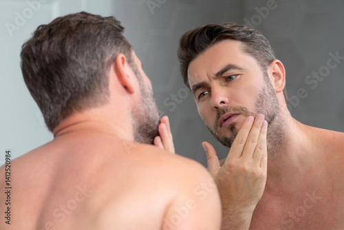Beauty face portrait of a beautiful man applying face cream. Moisturizing skincare cream for man. Mask, skin lifting and anti-aging effect. Beauty male face concept. Skincare and aging. Face cosmetic.