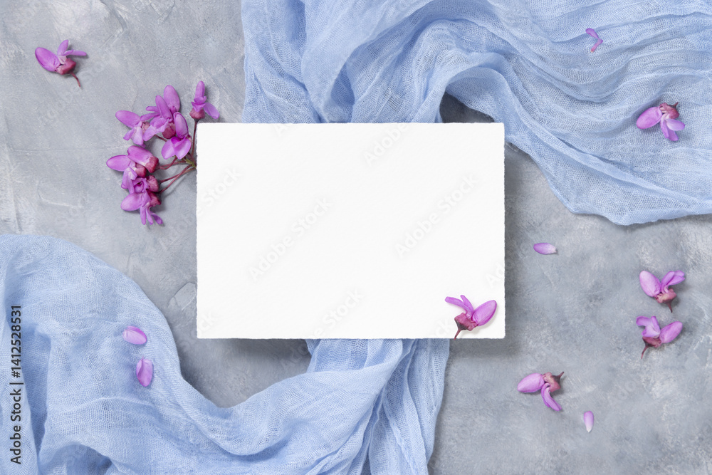 Blank card on fabric near wild purple flowers top view on gray, spring wedding mockup