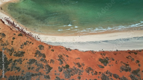 drone image of red sand dunes meeting the ocean