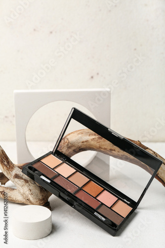 Decorative plaster podiums, palette of eyeshadows and tree branch on white table