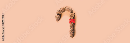 Caramel cane with bow of cedar cones for decoration. Banner.
