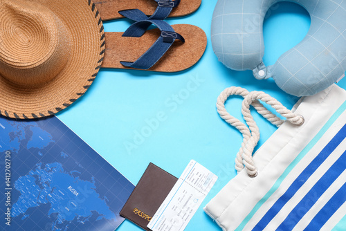 Frame made of travel pillow, passport and beach accessories on blue background