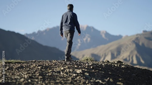 4K footage of Indian man taking a walk on a rugged mountain ridge in Ladakh, Lamayuru moonland of India, soaking in the view.