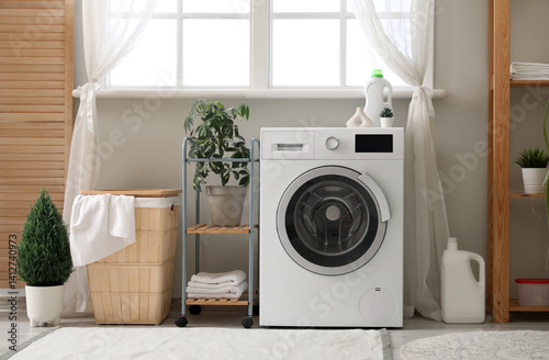 Obraz na płótnie Washing machine, basket with laundry and houseplants near window in room w salonie