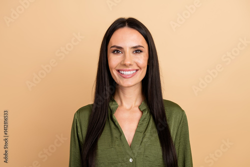 Confident young businesswoman smiling against beige background in green shirt