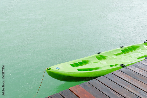 Obraz na płótnie green kayak is tied to wooden dock on calm, rainy day, creating serene and peaceful scene w salonie