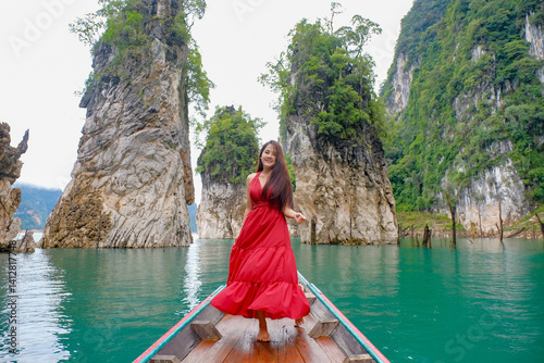 Obraz na płótnie woman in red dress joyfully stands on boat surrounded by stunning limestone cliffs and turquoise water w salonie