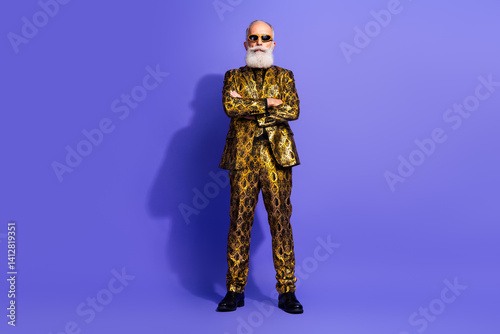 Charismatic Elderly Man in Extravagant Golden Suit on Purple Studio Background Standing Confidently with Folded Arms