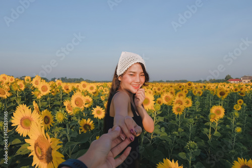 Obraz na płótnie woman in sunflower field smiles while holding someone hand, wearing white knit hat and black dress w salonie