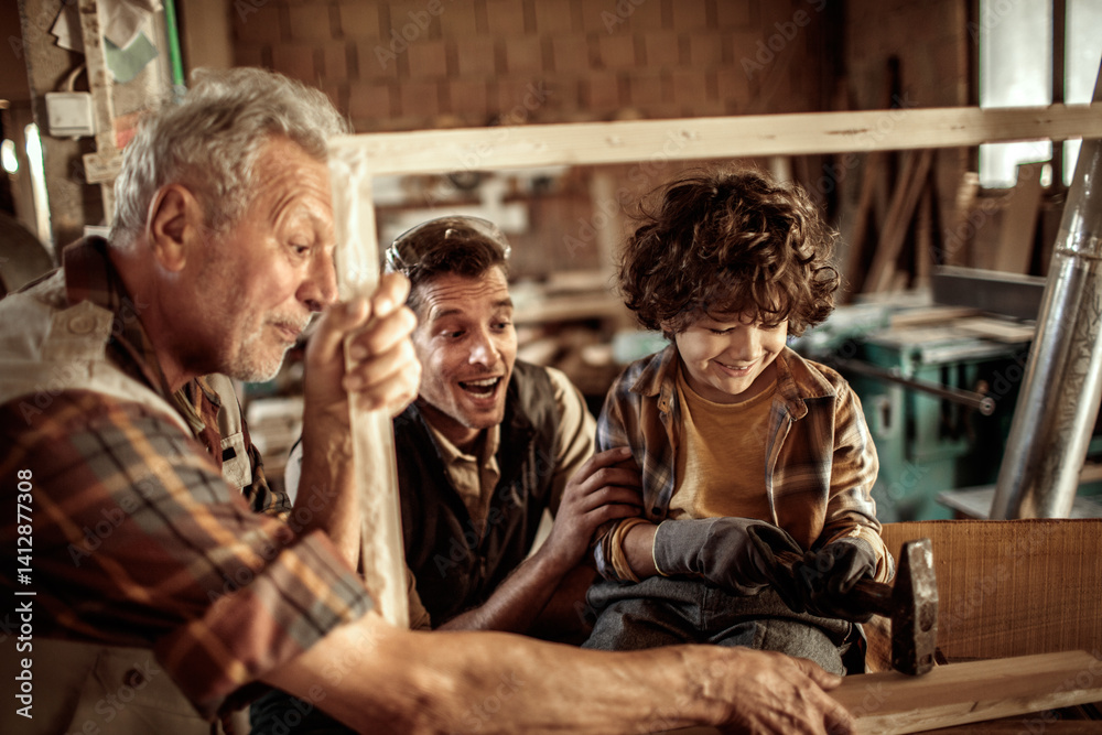 Happy grandfather teaching grandson carpentry with father in workshop Happy grandfather teaching grandson carpentry with father in workshop