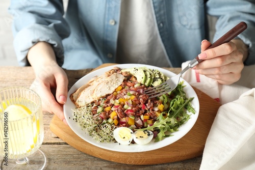 Obraz na płótnie Woman eating delicious salad with brown rice at wooden table, closeup w salonie