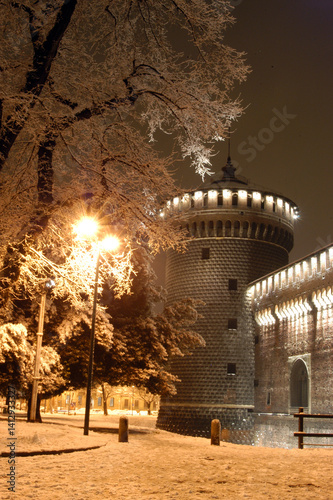 Night view of the Sforza Castle in Milan with the trees covered in a light snowfall