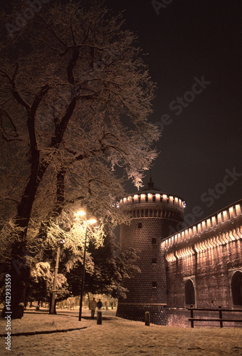 Night view of the Sforza Castle in Milan with the trees covered in a light snowfall
