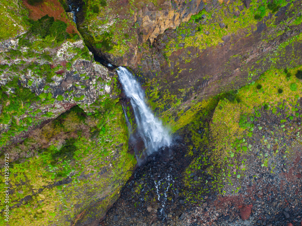 Stunning waterfall cascading down a rocky cliff surrounded by lush greenery