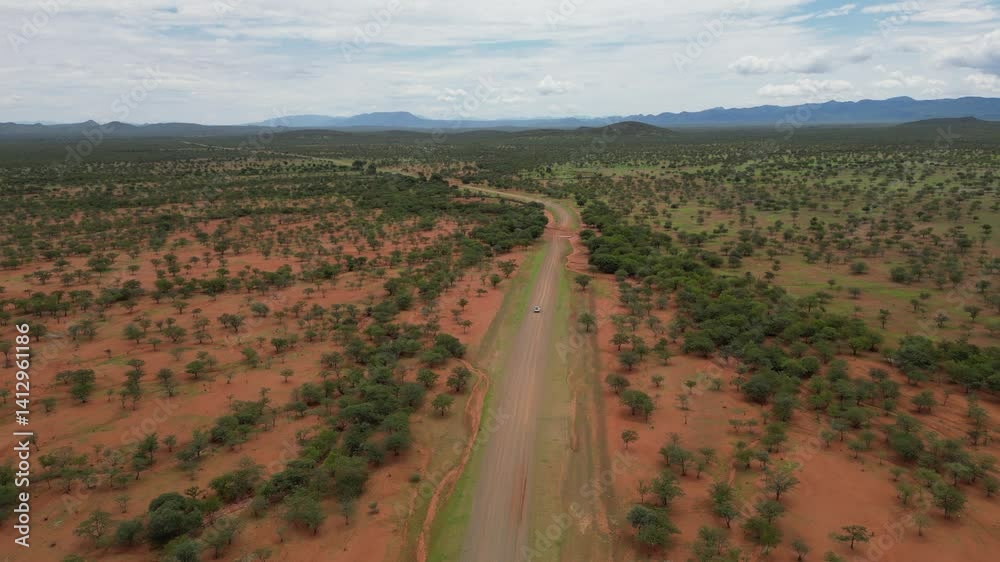 Drone view of a car driving on a road in the vast landscape of Savannah under cloudy sky in Namibia Drone view of a car driving on a road in the vast landscape of Savannah under cloudy sky in Namibia